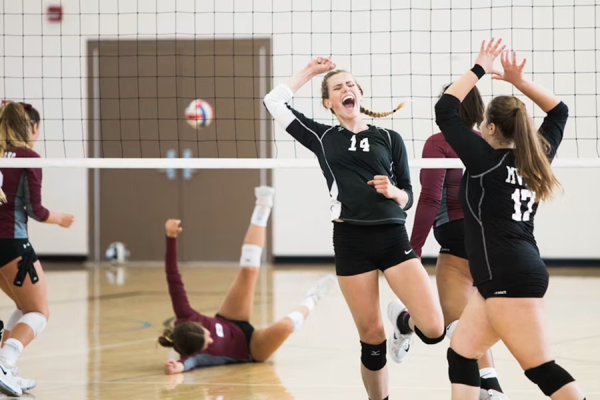Volleyball players celebrating a point at the net